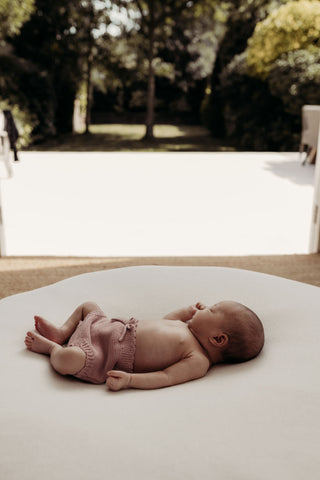 sleeping baby on beanbag next to sunny garden 
