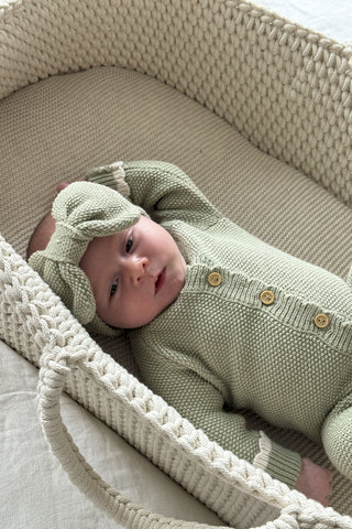 Baby in moses basket wearing sage green bow headband and romper