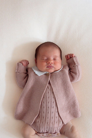 Sleeping newborn baby girl wearing pink knitted cardigan and bodysuit