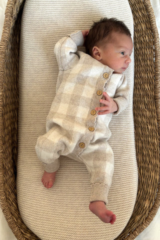 baby in moses basket wearing checkered knit romper