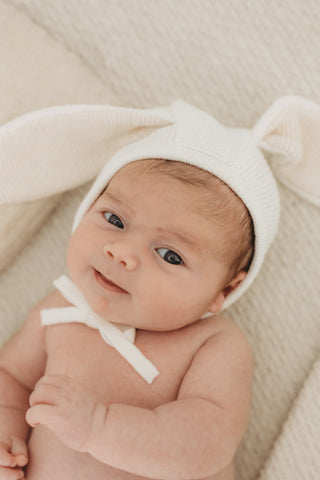 Baby wearing a knitted white bunny ear bonnet