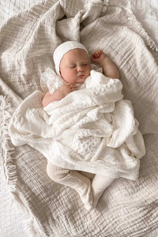 Sleeping baby in knitted white bonnet blanket