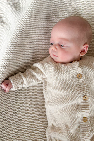 baby wearing knitted baby romper lying on blanket