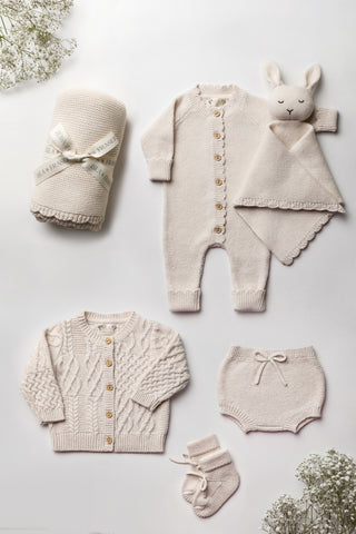Neutral Knitted Baby Gift Set flatlay: blanket, romper, bunny comforter, cardigan, bloomers, and booties