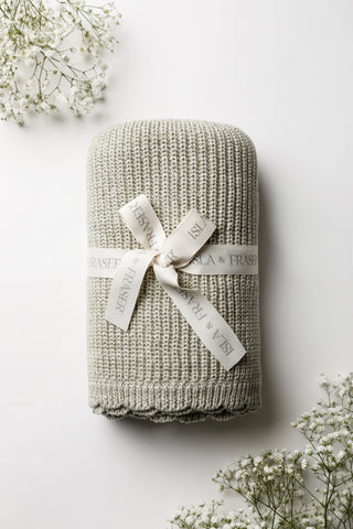 Sage Green knitted baby blanket with a scalloped edge and tied with an Isla and Fraser ribbon