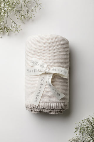 Cream knitted blanket with a beige scalloped trim tied with an Isla & Fraser ribbon