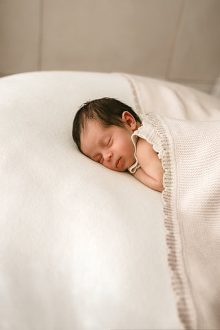 Sleeping baby with a beige scalloped edge and a matching blanket