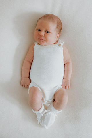 Baby wearing white knitted romper and booties