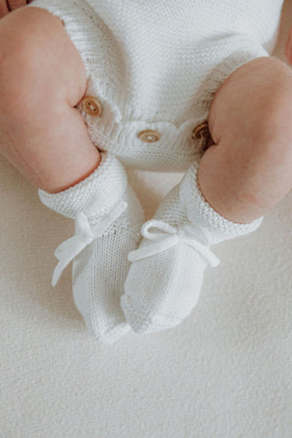 Baby wearing white knitted baby booties