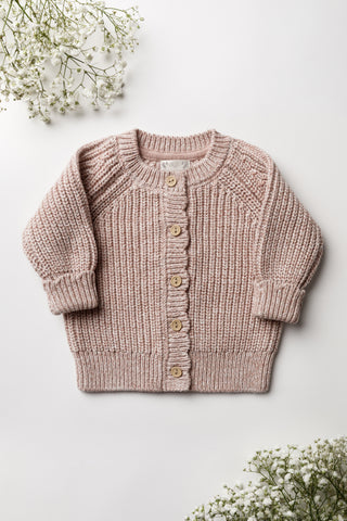 Light pink knitted baby cardigan on a white backdrop