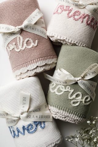 Group of embroidered named baby blankets tied with Isla & Fraser ribbons