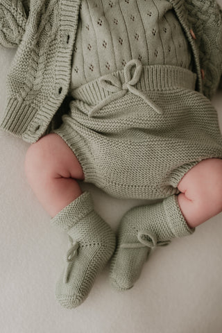 Baby wearing sage knitted outfit