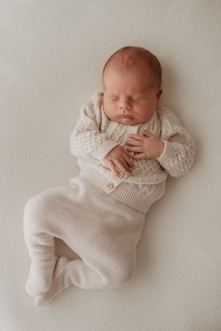 Baby wearing oat cable knit cardigan and trousers