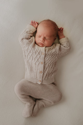 Baby wearing grey knitted cardigan and trousers 