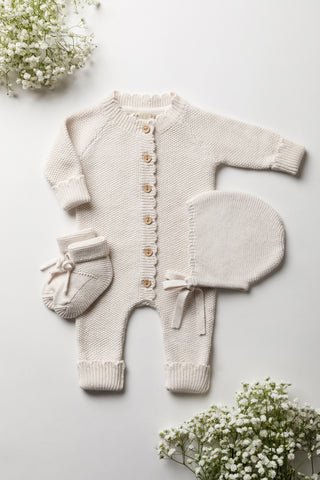 Neutral knitted baby romper, booties, and bonnet