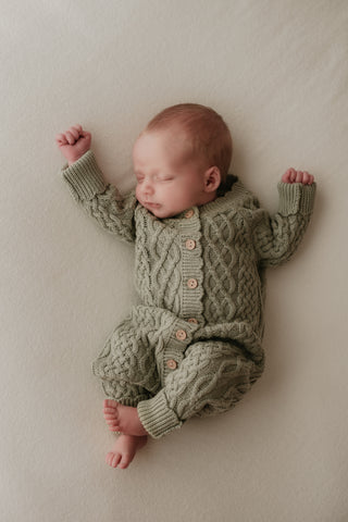 Newborn baby wearing a green cable knit romper