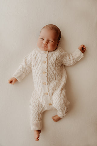 Baby wearing cream cable knit romper