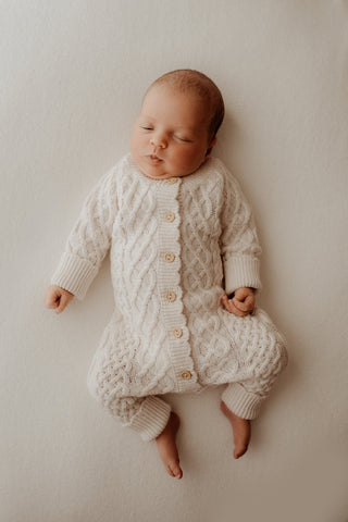 Baby wearing cream cable knit romper