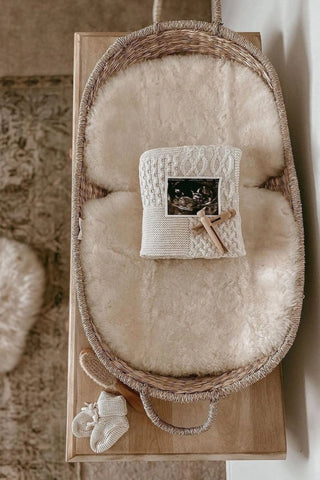 Basket with sheepskin liner and folded baby blanket with pregnancy scan and baby booties