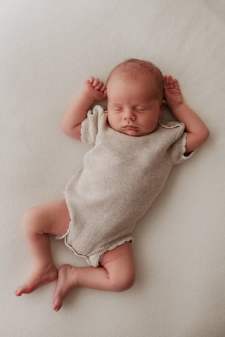 Sleeping baby wearing grey bodysuit
