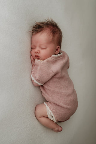 Baby wearing pink knit bodysuit 