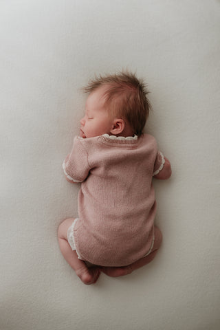 Baby wearing pink bodysuit with cream scalloped edge