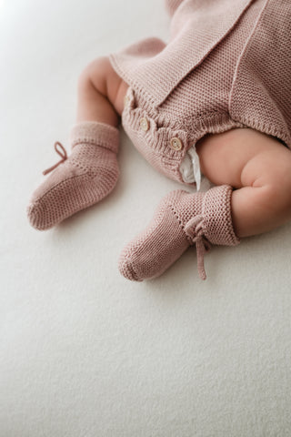 Baby wearing pink knitted outfit and booties 