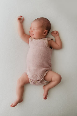 Baby wearing a pink knitted romper