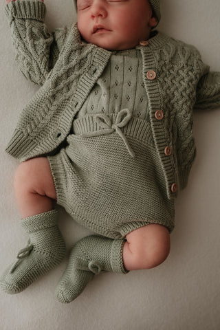Baby wearing sage green knitted outfit