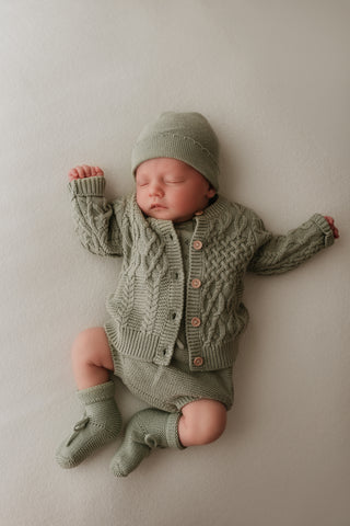 Sleeping baby wearing sage green knit outfit