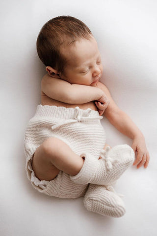 Sleeping Newborn baby wearing knitted bloomers and booties