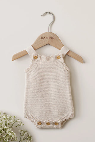 Knitted beige baby romper on a wooden Isla & Fraser hanger