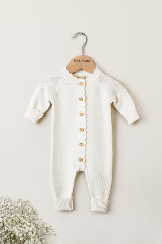 White knitted baby romper on a wooden Isla & Fraser hanger