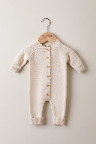 Knitted Baby Romper with buttons on an Isla & Fraser wooden hanger