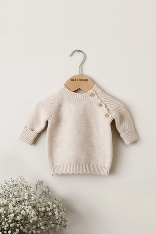 Beige baby jumper on a wooden Isla & Fraser hanger