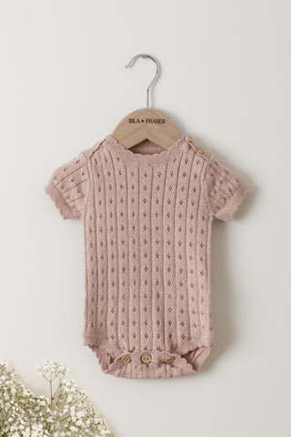Pink Pointelle knit baby bodysuit on a wooden Isla & Fraser hanger