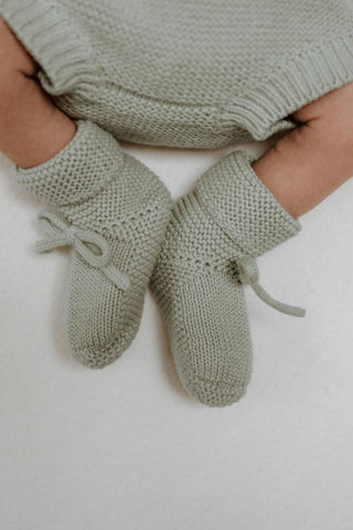 Baby wearing khaki green knitted booties