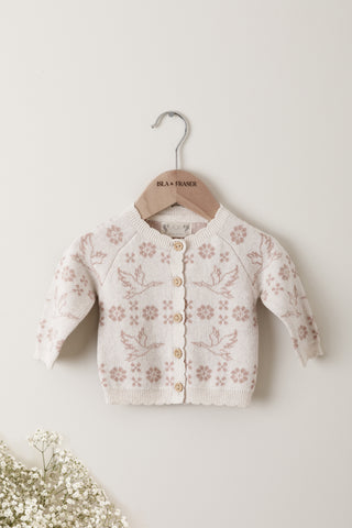 Knitted Baby Cardigan with flower and stork pattern on a wooden Isla & Fraser hanger