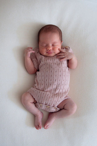 sleeping newborn baby in pink pointelle bodysuit