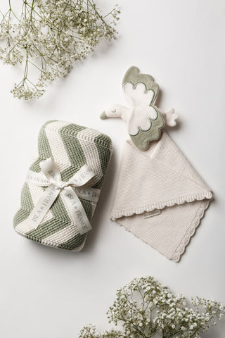 Knitted Baby Blanket in Sage and Cream Chevron Stripe tied with an Isla & Fraser Ribbon next to a Knitted Stork Baby Comforter