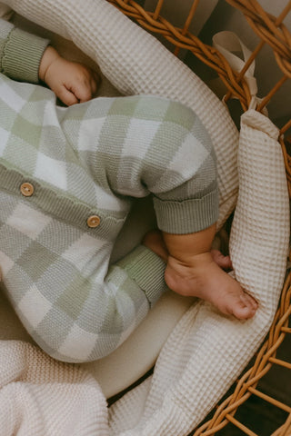 Baby feet in moses basket wearing sage gingham romper