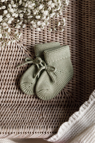 Sage Green Knitted Baby booties in basket with flowers