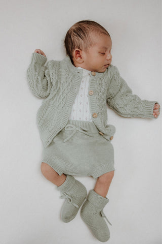 Sleeping newborn baby wearing sage green knitwear