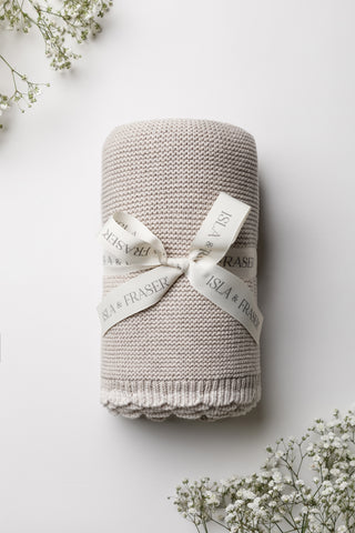 Knitted grey baby blanket with scalloped cream border tied with an Isla and Fraser ribbon 
