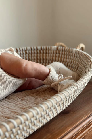Baby in basket wearing knit booties