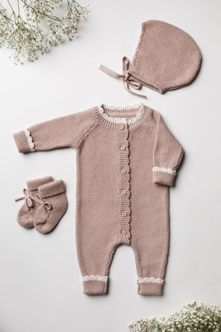 Pink knitted baby booties, romper, and bonnet