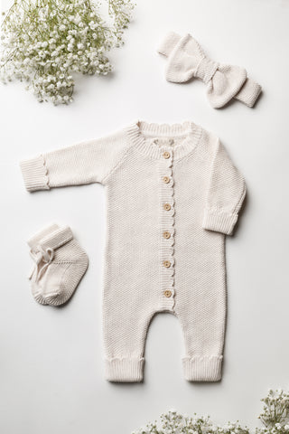 Knitted baby gift set in cream, comprising of booties, romper and bow headband.