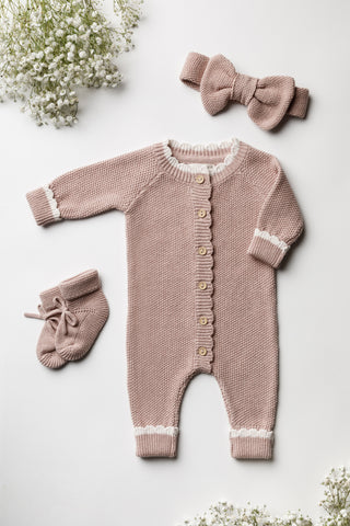 Knitted pink baby outfit comprising headband, booties, and romper