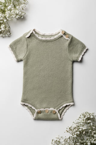 Knitted sage green baby bodysuit with cream scalloped edging and wooden buttons