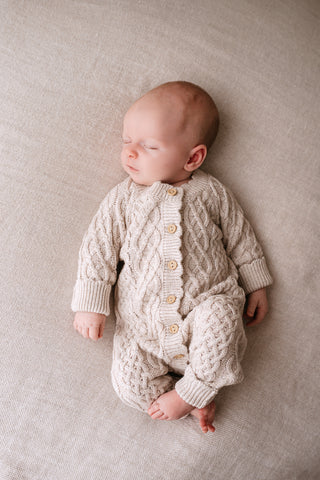 Sleeping baby wearing a neutral cable knit romper